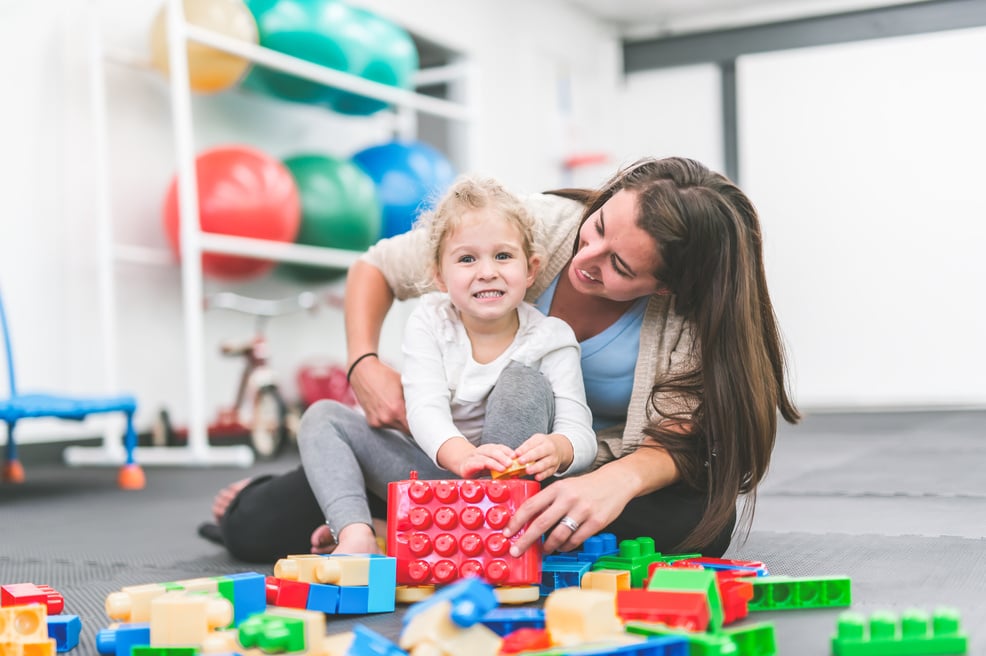 A female occupational therapist is doing rehabilitation with a child patient